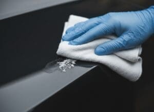 Gloved hand wiping crystalline AdBlue residue from a vehicle surface
